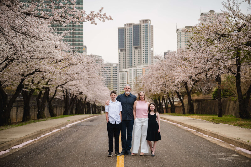 Family of four standing under cherry blossoms in Seoul — sharing expat reflections and parenting stories on Leaving Main Street