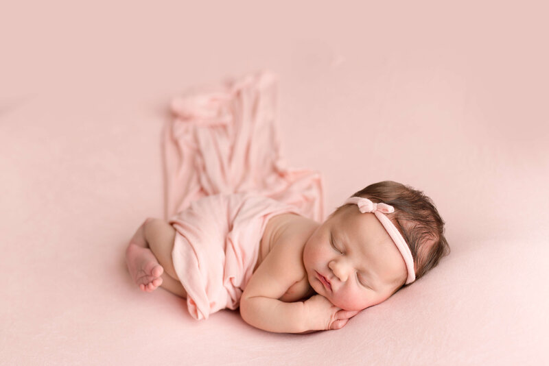 Infant girl on pink fabric with pink headband