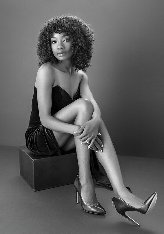 A striking black-and-white portrait of a woman in a sleek black dress