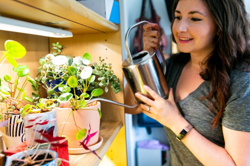 Woman watering her plants underneath a Modsprout grow light