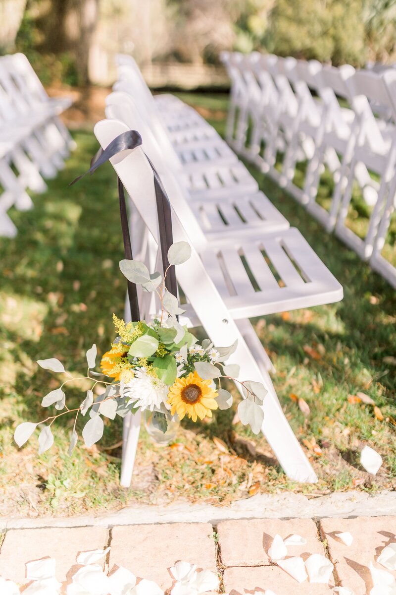 Ceremony seating with white chairs and sunflower bouquets