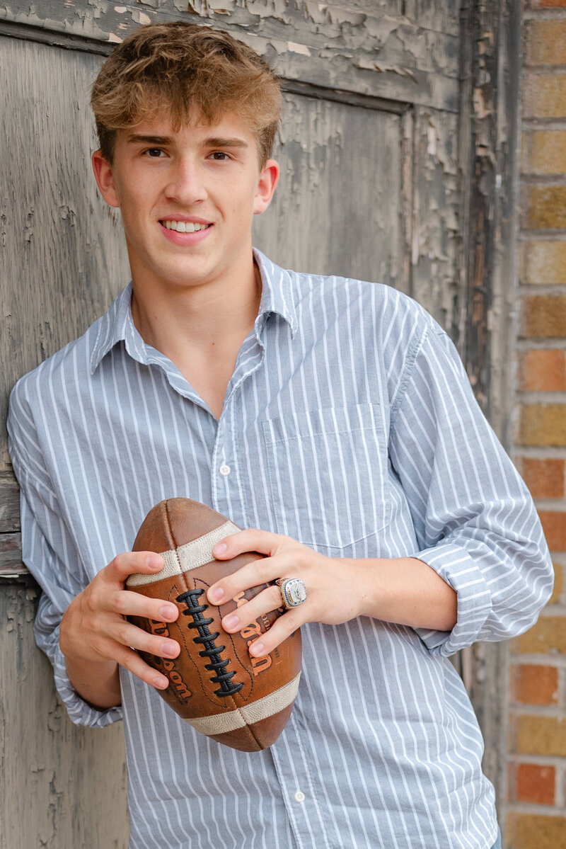 Senior boy holding a football for his portrait session.