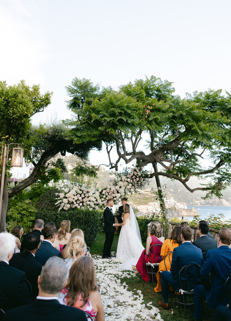 Bride and groom exchanging vows with the Amalfi Coast cliffs and sea in the background.
