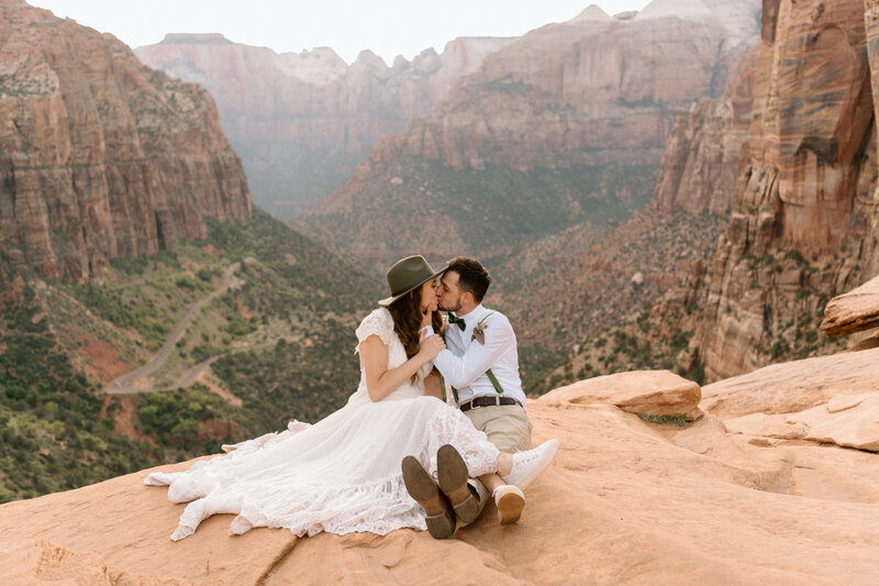bride wearing an olive green boho wide brimmed hat on the edge of Zion overlook