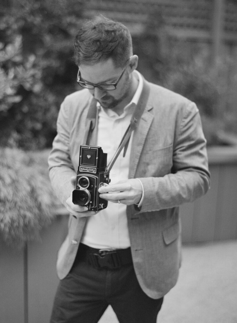 Bradley Burckel photographing a wedding with a vintage film camera in hand