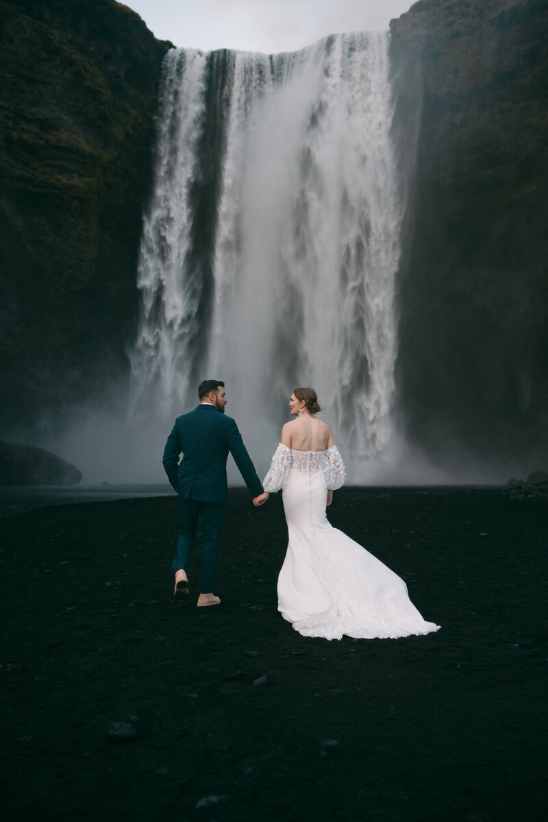 A wedding couple standing on a mountain hugging.