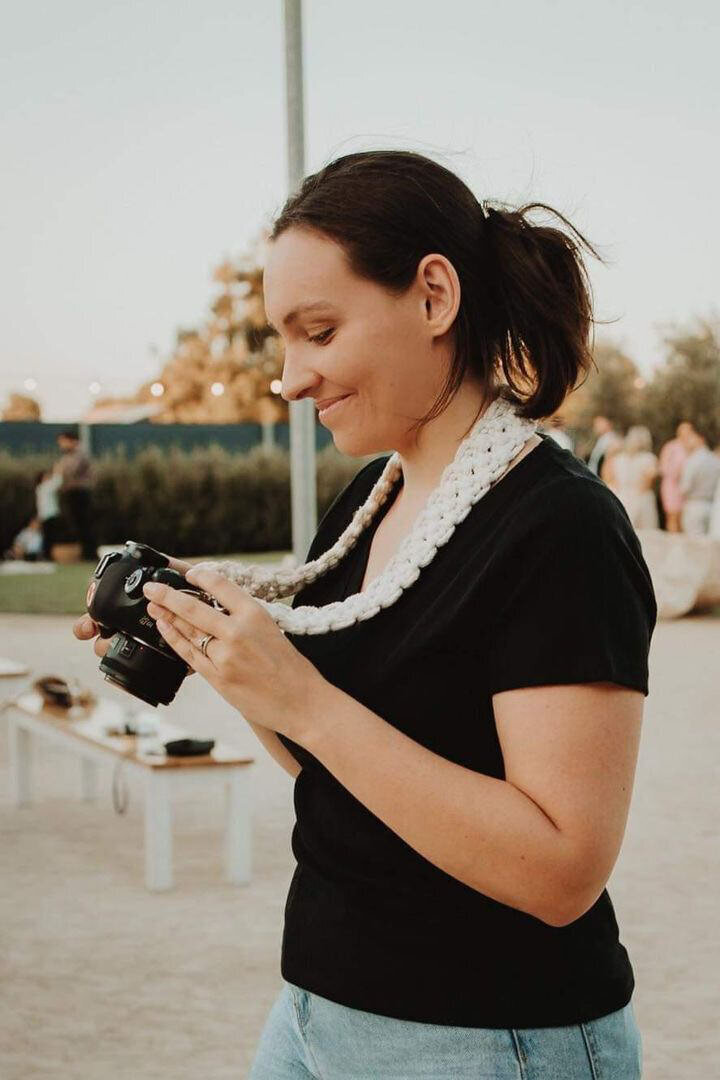 Side shot of Emme Jae Photography looking at camera and smiling at photos just taken