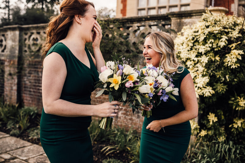 Bridesmaids in green dresses with bouquets laughing