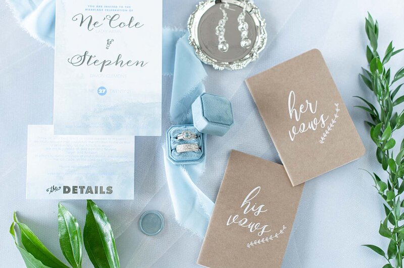 A detailed wedding flat lay shows rings and vow books