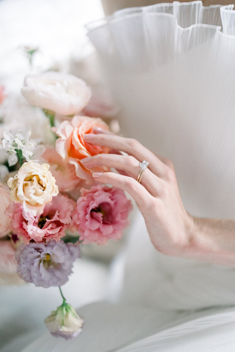 spring bridal bouquet in pastel colors with elegant bridal hand with bridal manicured nails and engagement ring