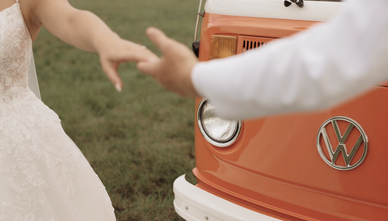 Couple holds hands in front of vintage VW bus