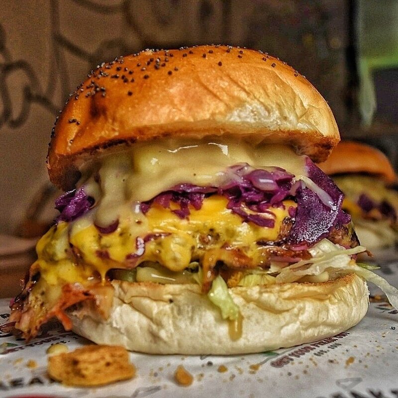 Large burger dripping with cheese, lettuce bacon and pickled cabbage