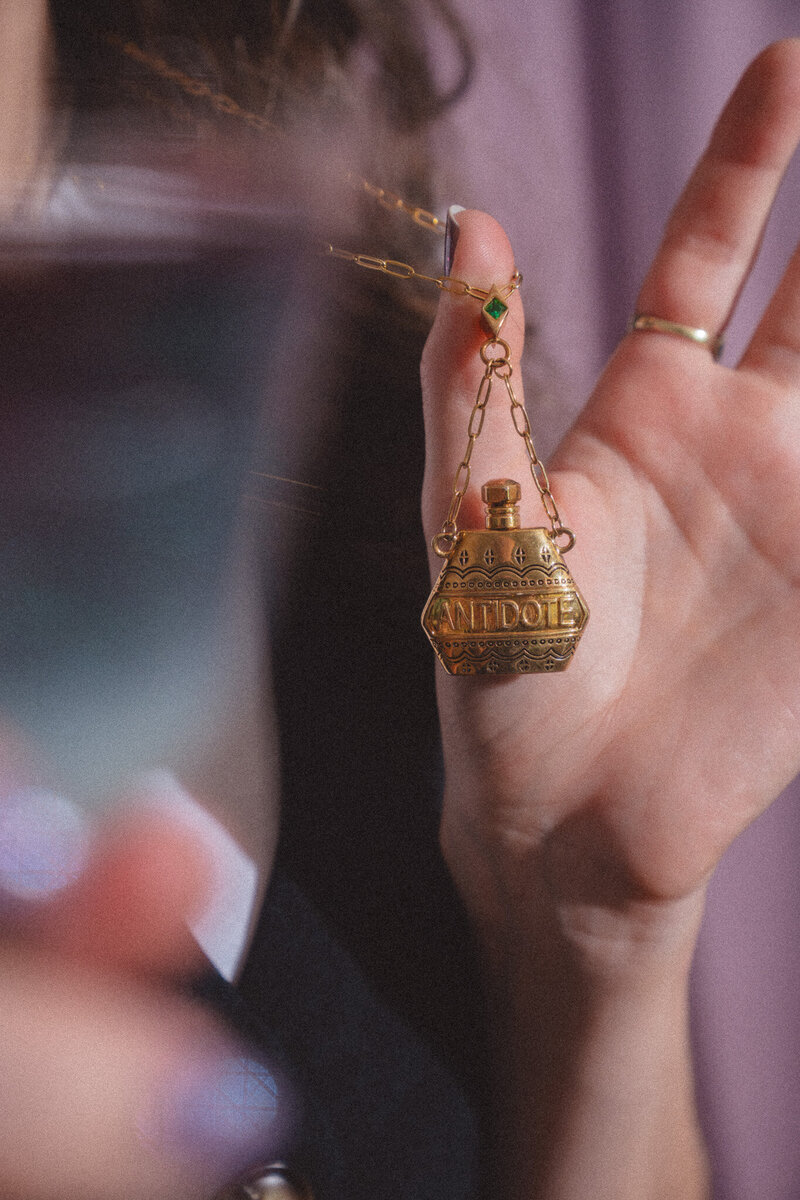 Photo of Cassie holding out her necklace's "antidote"  bottle charm - as in, an antidote to watered-down brand messaging. Mettle & Tonic