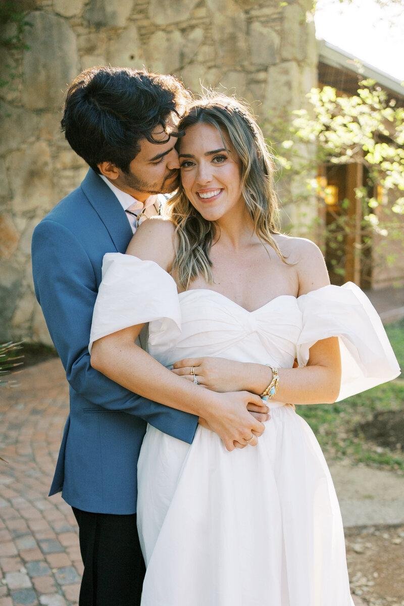 Groom posing with hands around bride