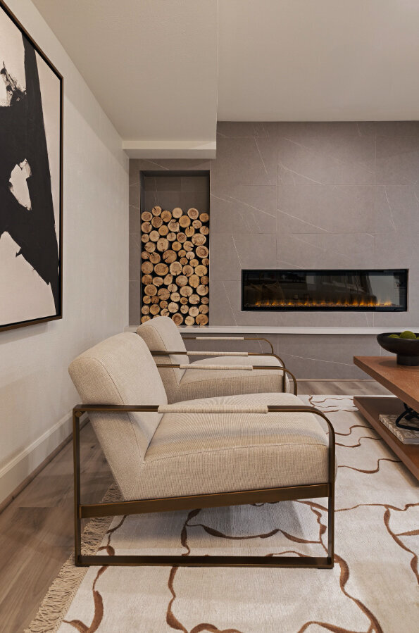 Modern mountain living room with modern furnishings, a log wall and marble fireplace in Park City, Utah. Designed by Sister Studio Interior Design
