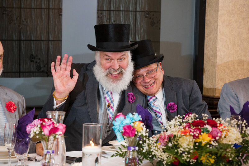 Couple in top hats seated at their wedding reception