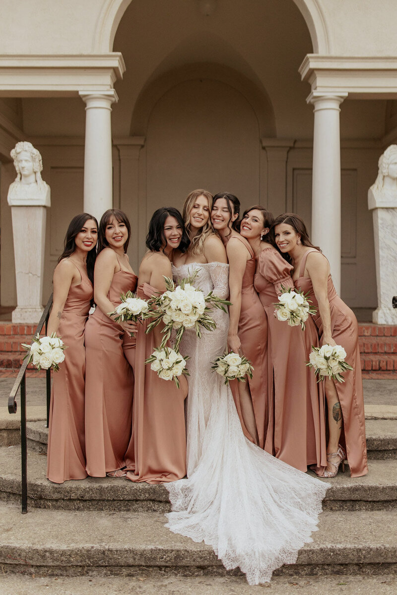 Bride with bridesmaids in satin dresses holding bouquets