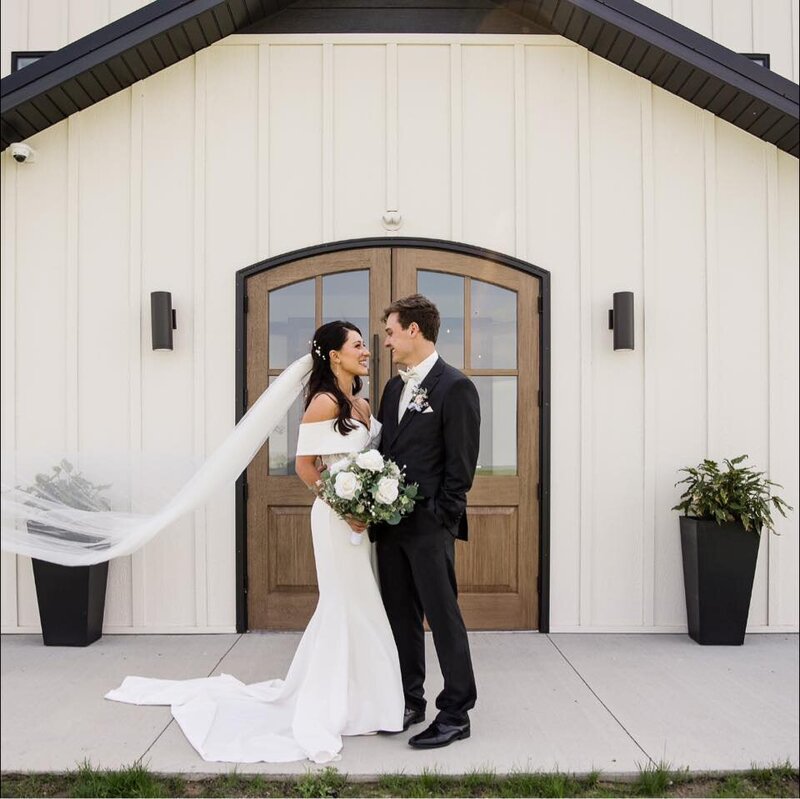 The bride and groom share a loving gaze outside the August House Venue, capturing a beautiful moment on their wedding day.