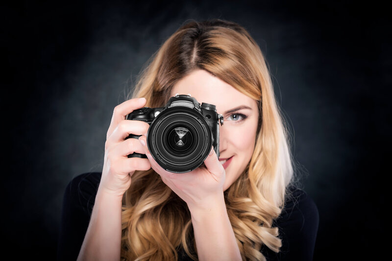 Blonde Woman With Camera against black backdrop