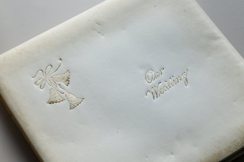 The cover of an old 1970s wedding album with visible stains, highlighting the need for restoration.
