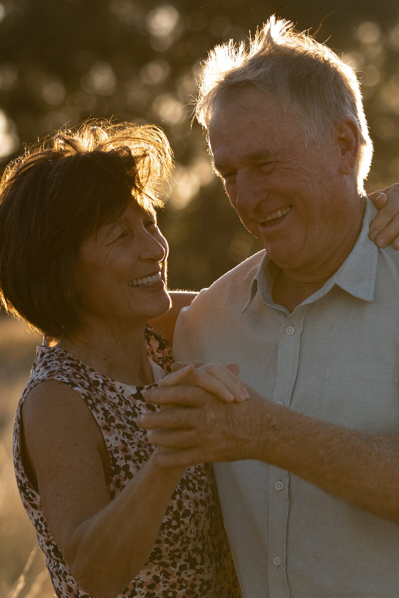 engaged couple walking through a field holding hands