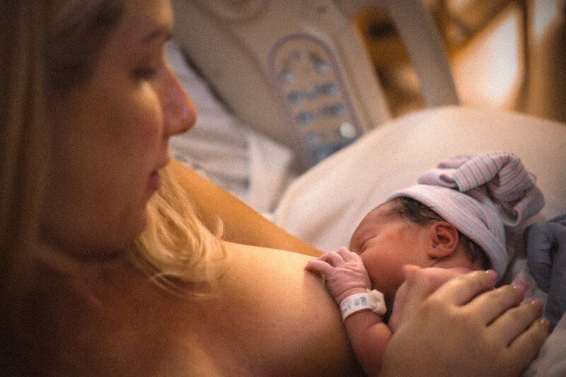 Mother nursing newborn baby at birth