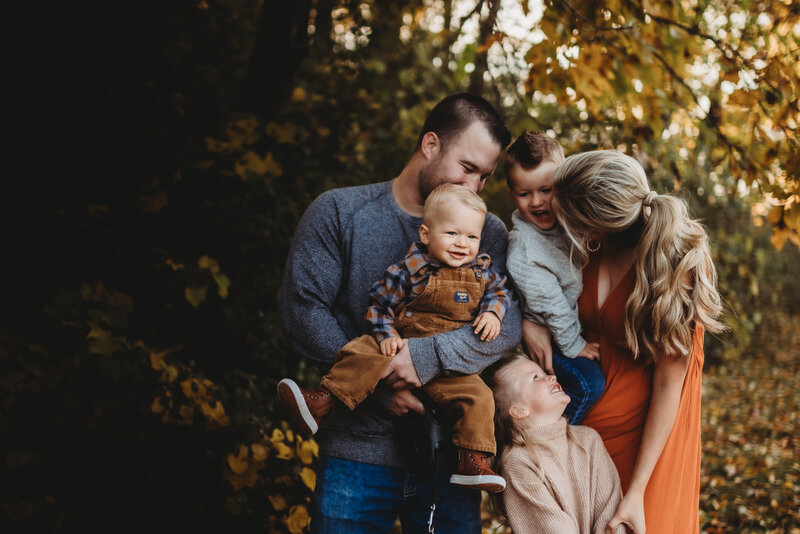 Family of 5 squeezed together laughing in a fall setting outdoors