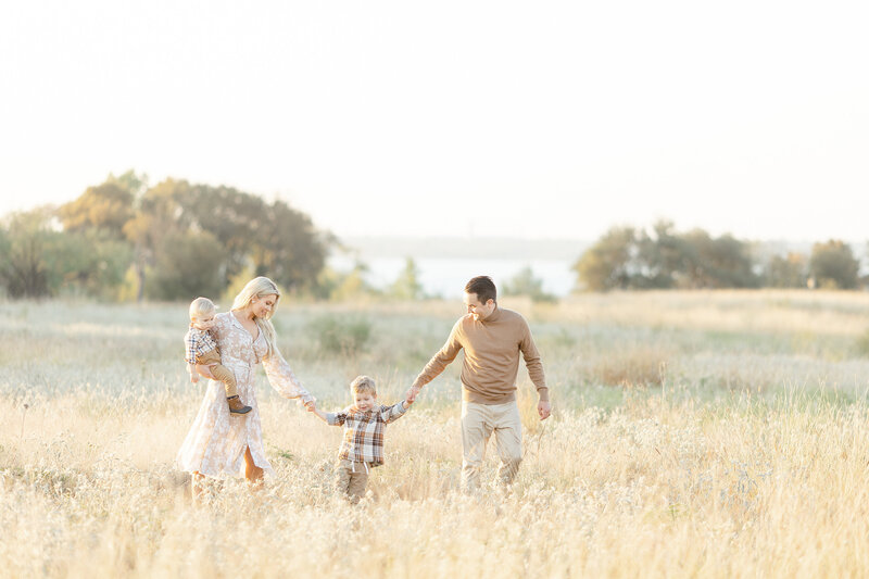 A family of 4 portrait taken while they are walking through a field at a local Dallas Texas park taken by a Dallas Family Photographer.