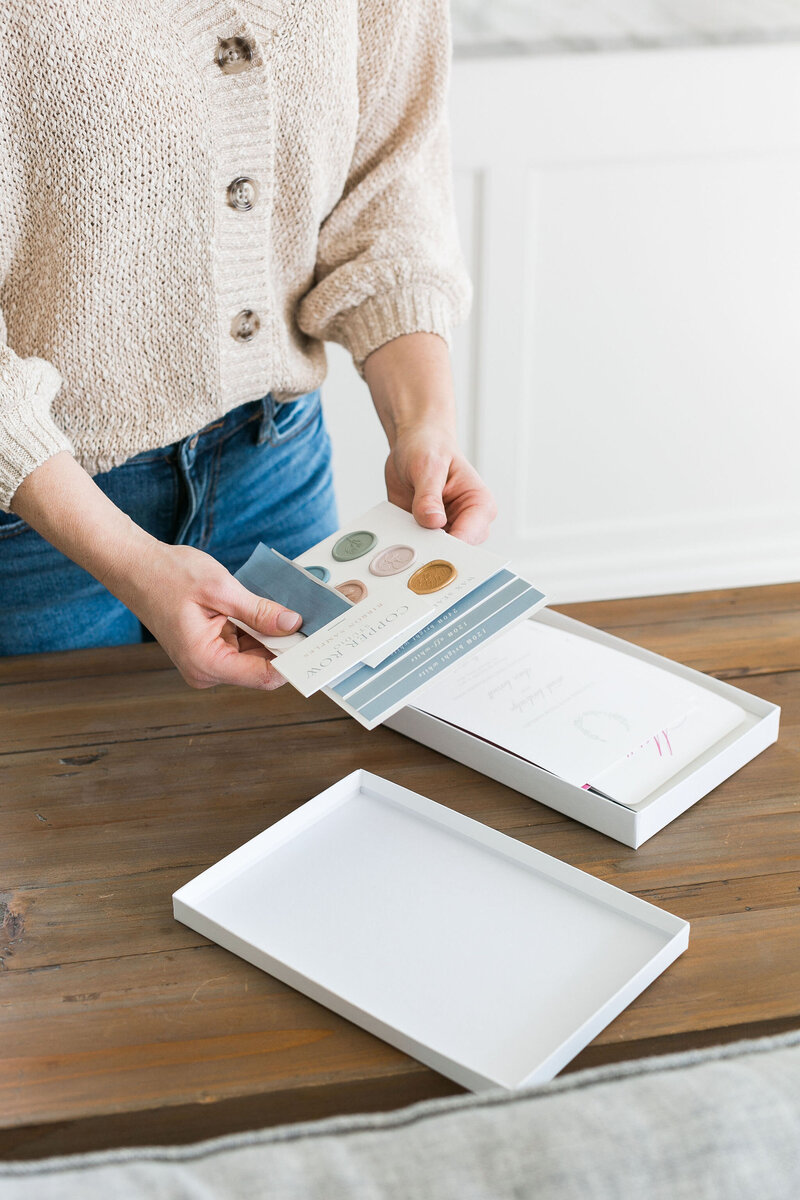 a woman's hands holding wedding invitation samples