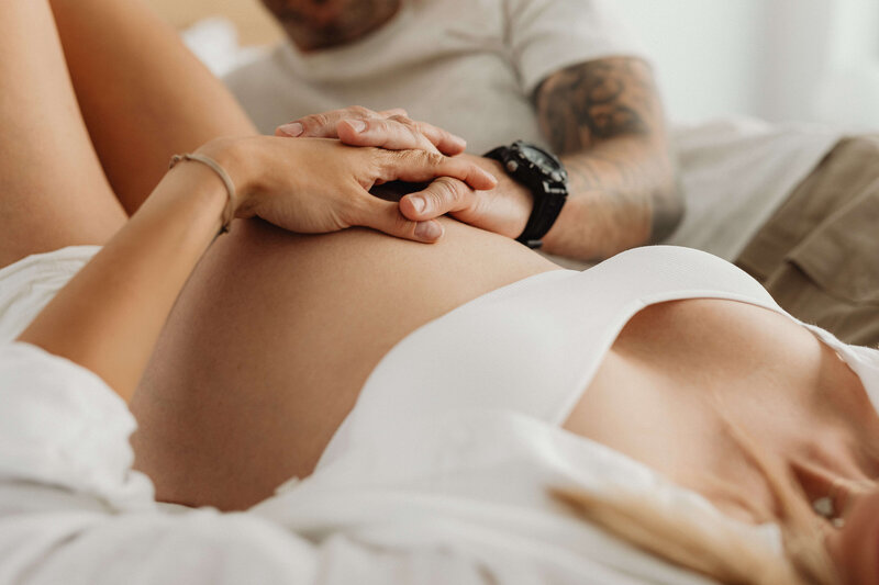 Pregnant woman laying down with hands on belly