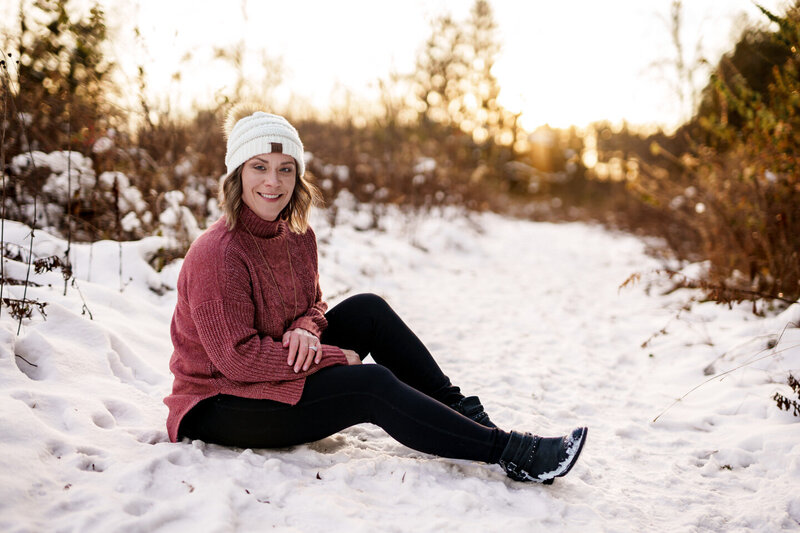 Jen Heller sitting in a snowy field at sunset
