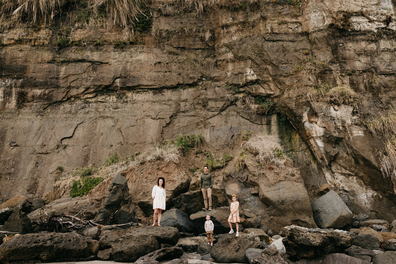 family standing in front of rock wall in capitola, california on the beach