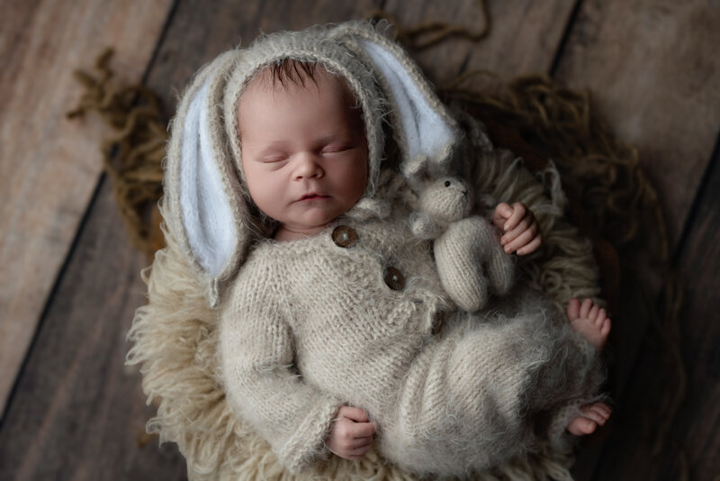 Rustic newborn portrait in a fluffy hand-knit bunny outfit with coordinating toy.