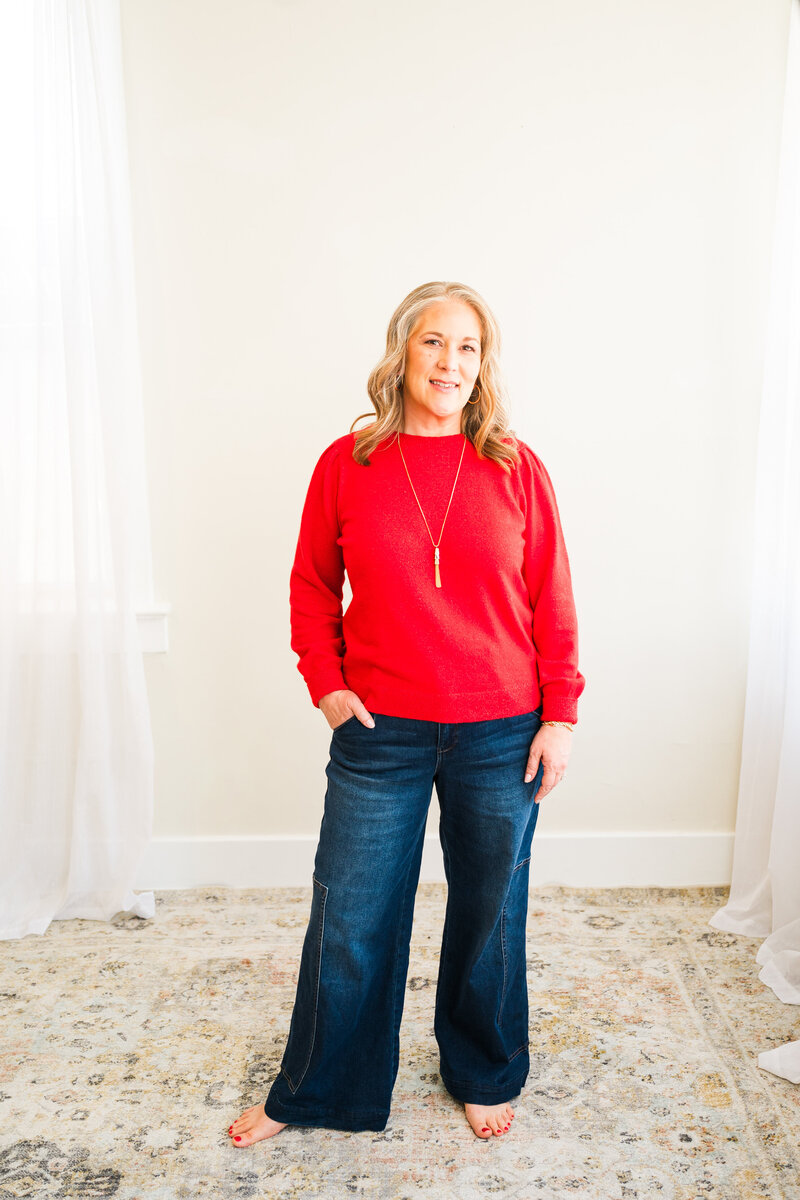 Woman standing in red sweater and jeans