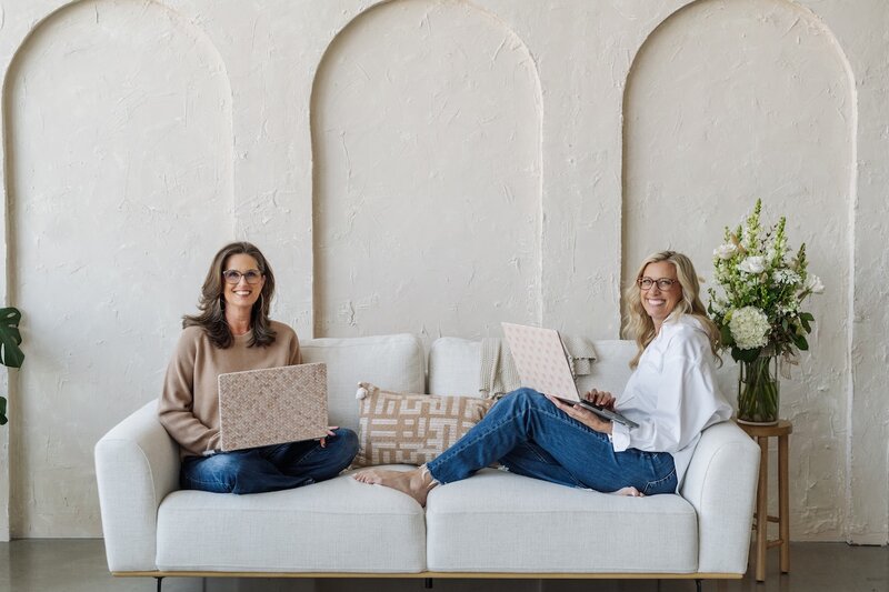 Two women working together on a laptop learning the ins and outs of running a profitable wedding venue.