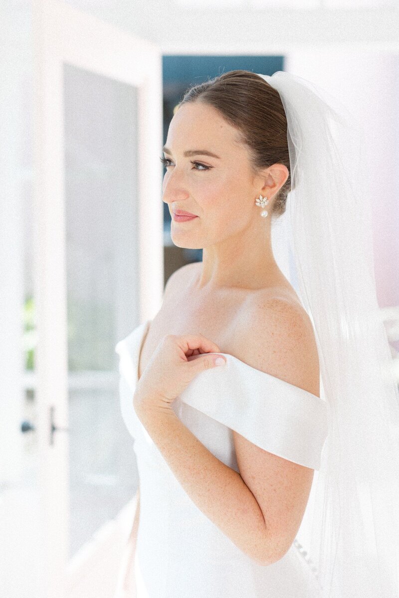 bride in off-the-shoulder wedding gown smiling off into the distance