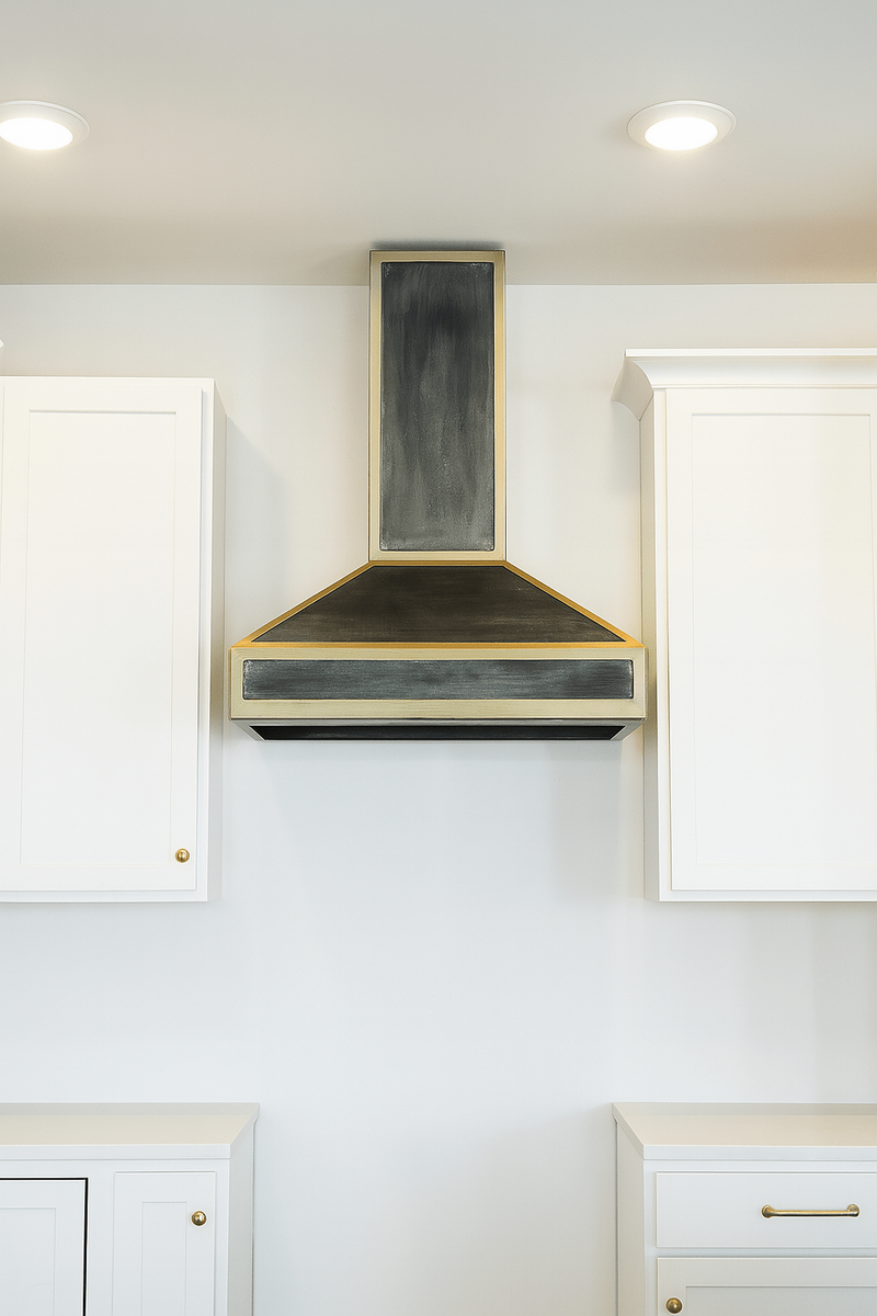 Handcrafted welded steel range hood with precision metalwork installed in a residential kitchen.