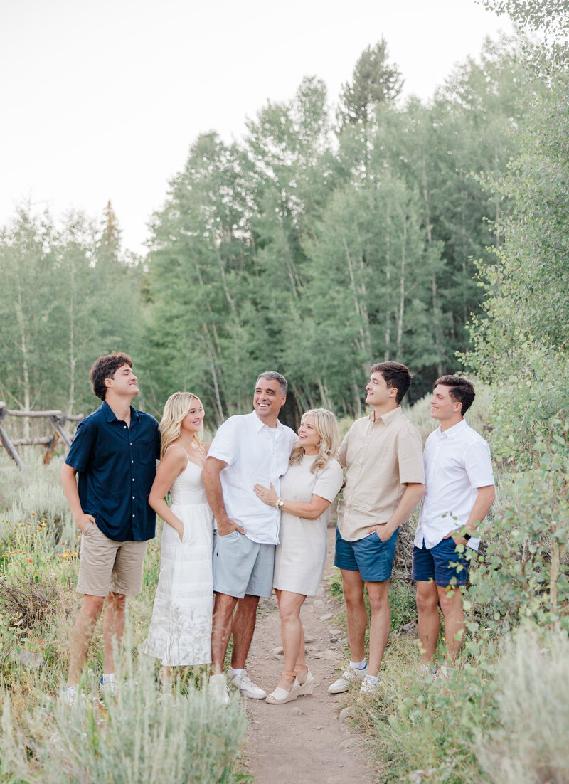 An image from a Breckenridge Photographer of a large family smiling at each other in a forest trail