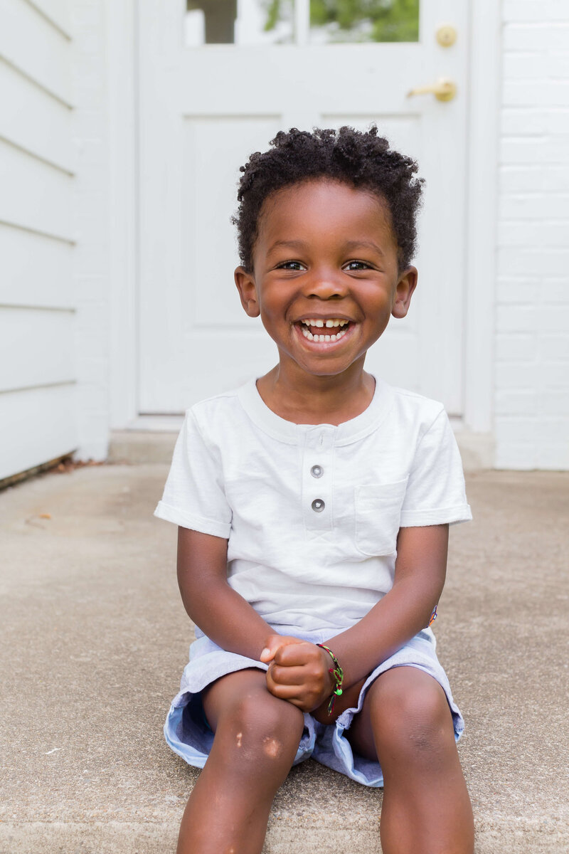 toddler smiling for camera wearing short sleeve white t-shirt