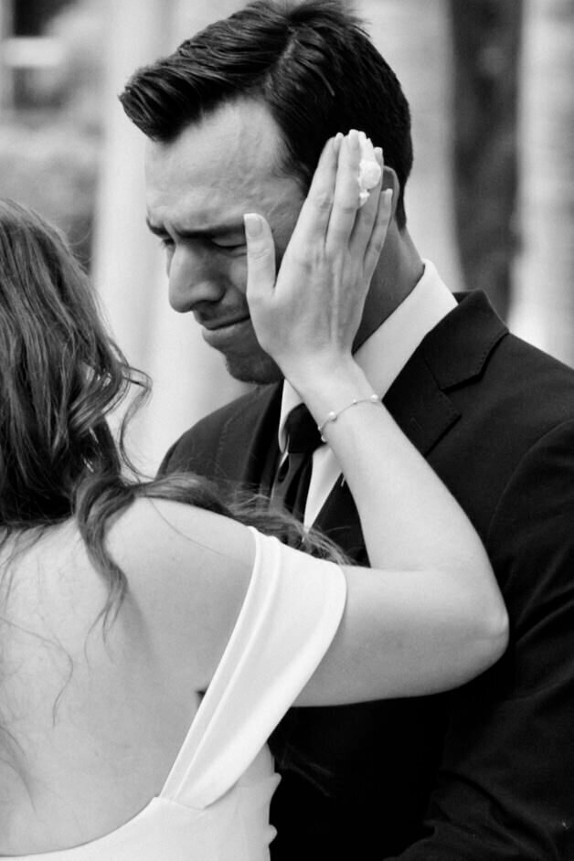 bride holding groom's face who is teary by Wedding Photographer South Florida