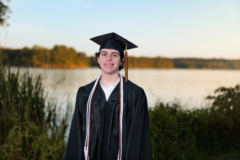 Senior Portraits by a lake in Holly Springs, NC leaning against a tree.