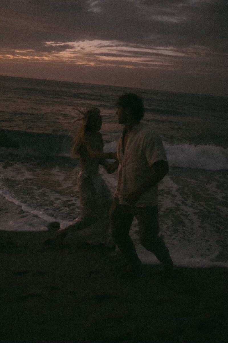 "Playful moment between a couple as they dance ion the beach