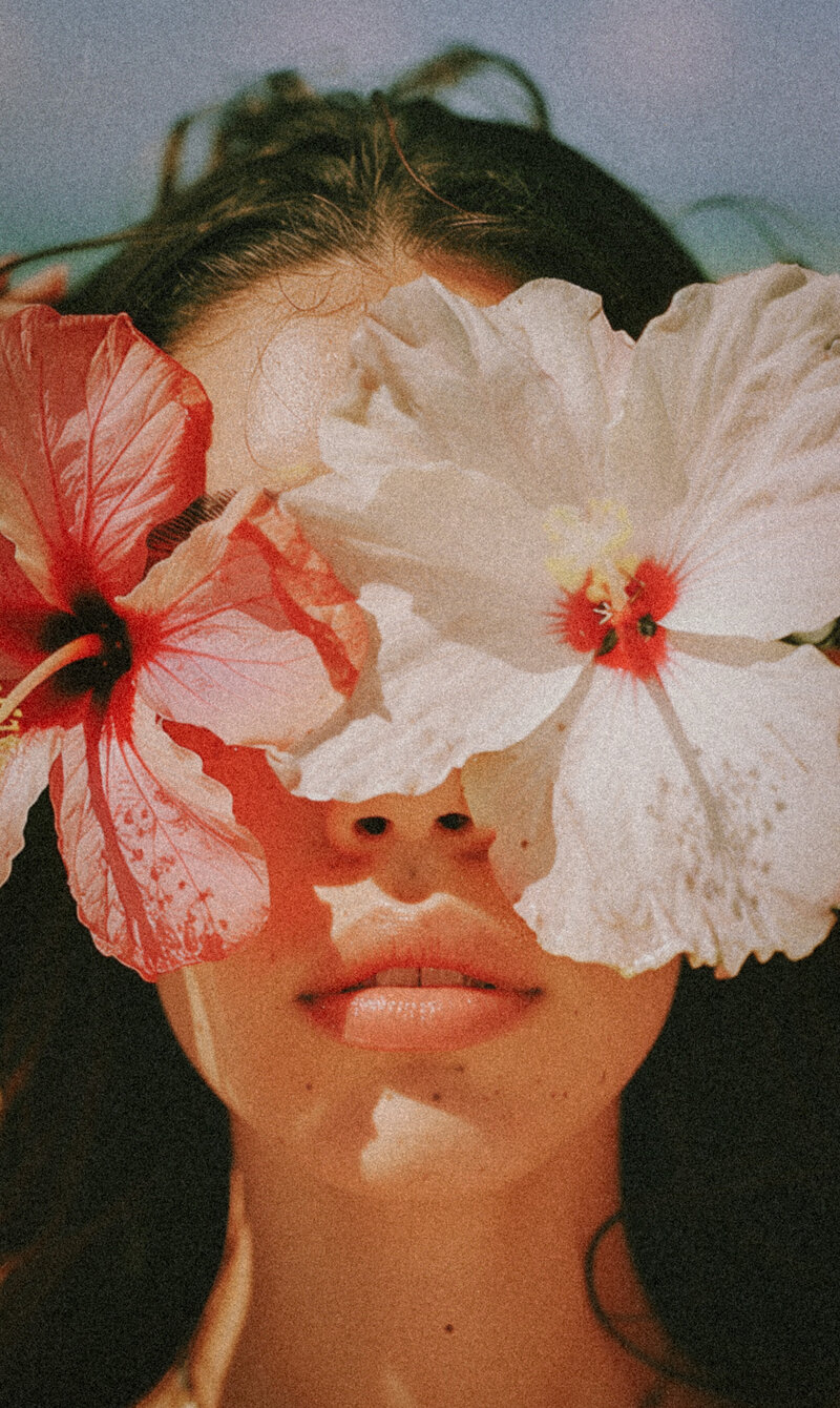 Woman's face covered by bright pink and white flowers