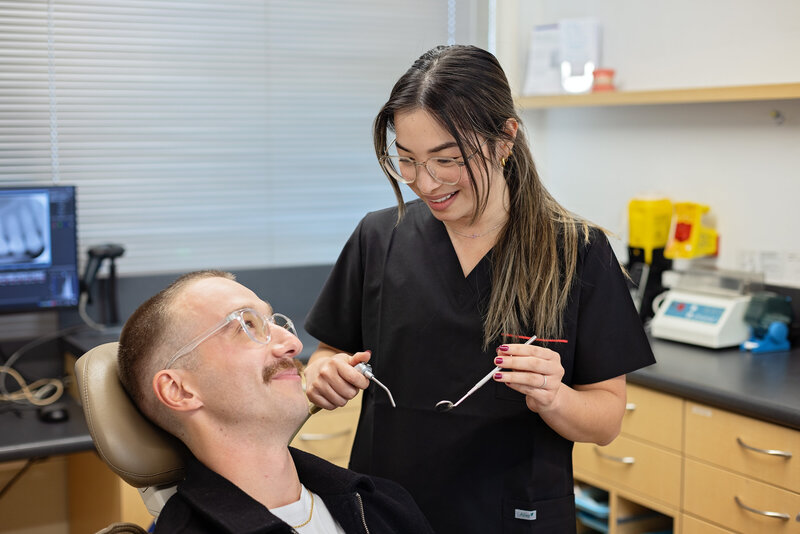 dentist holding tools and talking to patient in chair