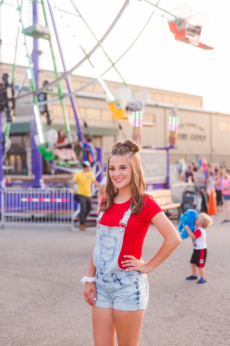 high school senior girl wearing black jumper with high heel sandels, also wearing a tan hat standing with hands on hips in front of Canton palace theater in Canton Ohio photographed by Jamie Lynette Photography Canton Senior Photographer