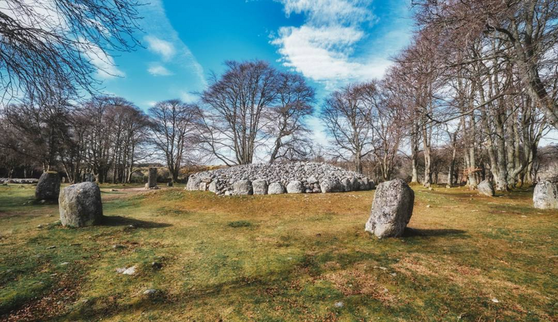 The Bronze Age stone circles of Clava Cairns near Inverness, surrounded by bare winter trees under a bright Scottish sky — a hauntingly beautiful stop on Kat Mackenzie’s Work in Progress Literary Tour, where myth, memory, and time converge.