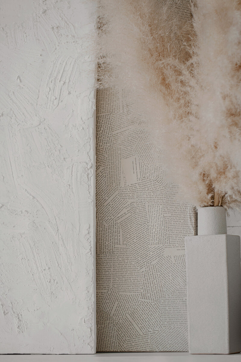 Neutral-toned modern vignette featuring a textured white plaster canvas, vintage book page collage, and a white ceramic vase with pampas grass—reflecting Sable & Rose’s aesthetic of blending creativity, storytelling, and elevated design.