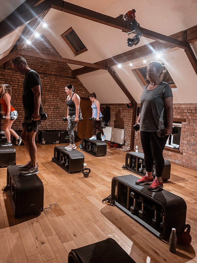 Two women in their late 40's lifting dumbbells in KT Chaloner group training class