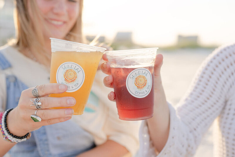closeup of friends cheersing their sundial iced teas on the beach in surf city during golden hour