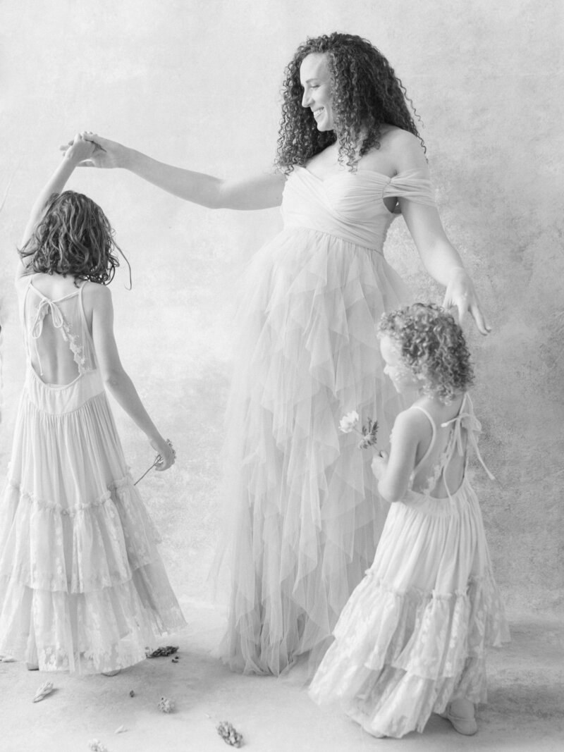 Mother in a soft tutu dances with her toddler during an in-home maternity session.